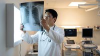 Male doctor examining chest x-ray film in modern medical facility. Healthcare professional analyzing lung radiograph for diagnosis and treatment planning.
