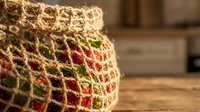 Fresh apples stored in eco-friendly jute mesh bag on rustic wooden kitchen counter, promoting sustainable zero waste lifestyle and organic produce storage.