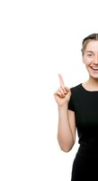 Young woman with fair skin and short brown hair wearing a black t-shirt, smiling brightly while pointing upward with one finger against a white background for advertising and promotional campaigns.