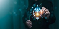 Businessman touching glowing lightbulb with digital innovation icons representing creative ideas and technological solutions for modern business growth.