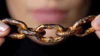 Rusty metal chain links held in hands against dark background, showing deterioration and aging effects of corrosion on industrial equipment. Close up macro photography.