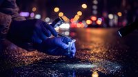 Forensic investigator in blue gloves collecting evidence at night crime scene with city lights bokeh background for police investigation work.