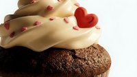 Chocolate cupcake with vanilla frosting topped with red heart and sprinkles for Valentine's Day celebration and romantic desserts.