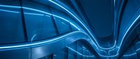 Futuristic blue neon light curves along sleek architectural interior, glowing lines creating dynamic modern design for tech and innovation backgrounds.