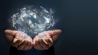 Hands holding glowing geometric crystal structure with holographic light effects against dark background for technology and innovation concepts.