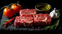 Raw marbled beef steaks with fresh ingredients on dark stone board, dramatic lighting emphasizes meat texture and cooking ingredients for gourmet meal preparation.