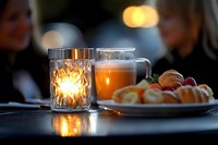 Cozy evening tea time with glowing candle, steaming mug and fresh pastries on table creating warm atmospheric dining scene for relaxation and comfort.