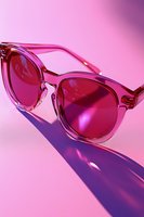 Trendy pink transparent sunglasses with tinted lenses on vibrant pink background creating dramatic shadow for fashion and summer style concepts.