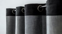Modern two-tone curtains with metal grommets in black and gray colors creating contemporary window treatment design, close up view showing fabric texture.