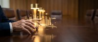 Businessman's hand on conference table with glowing golden holographic cityscape projection, representing urban development, real estate investment, and future growth strategy.