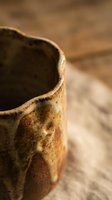 Handmade ceramic pottery cup with rustic brown glaze on wooden surface showcasing artisan craftsmanship and traditional pottery techniques for home decor.