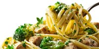 Delicious pasta dish with spaghetti, chicken pieces, broccoli, and herbs on a fork, showcasing homemade Italian cuisine for food photography.