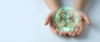 Hands cupping a glowing green plant hologram symbol, representing sustainability, eco-friendly innovation, and environmental care concepts.