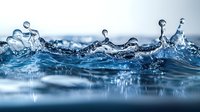 Dynamic water surface with splashing droplets and crown-shaped formations captured in macro photography against blurred blue background, showing liquid motion and ripples.
