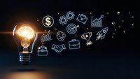 Glowing light bulb with business icons floating on dark background representing innovation, entrepreneurship and creative solutions for success.