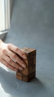 Close-up of a person's hand resting on a wooden block puzzle, demonstrating problem-solving and strategic thinking for business and educational concepts.