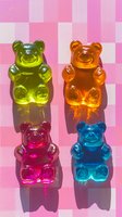 Colorful gummy bears candy on pink checkered background with dramatic shadows. Green, orange, pink and blue translucent jelly sweets arranged in square composition.