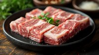 Raw marbled beef steaks on black plate with fresh herbs, premium cuts ready for grilling or cooking, restaurant quality meat preparation for culinary use.