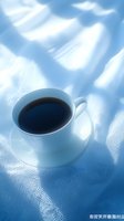 White cup of black coffee on textured blue fabric with soft morning light creating gentle shadows. Perfect for food blogs.