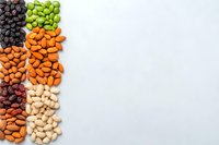 Colorful assortment of raw nuts and dried fruits arranged in vertical stripes on light gray background with copy space, top view composition.