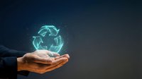 Businessman hand holding glowing recycling symbol with digital particles on dark background, representing sustainability, environmental responsibility, and green business solutions.