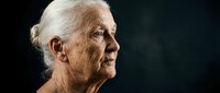 Senior woman with white hair in profile against dark background, suitable for healthcare, aging, wellness, and editorial content.