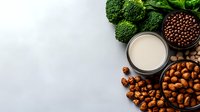 Plant based milk with hazelnuts, broccoli and chocolate soy beans on gray concrete background. Healthy vegan protein sources and dairy alternatives.