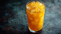 Refreshing orange cocktail with ice cubes in tall glass on dark textured background. Vibrant cold summer drink with dramatic lighting.