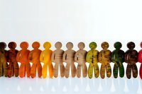 Colorful gummy bear candies lined up in gradient color order from brown to red on white reflective surface showing diversity and unity concept in food art.