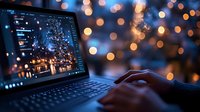 Laptop with photo editing software open at night, hands typing on keyboard against blurred bokeh lights background. For creative work and photography.