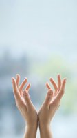 Open hands reaching upward in prayer or meditation gesture against soft blurred natural light background for wellness and spirituality concepts.