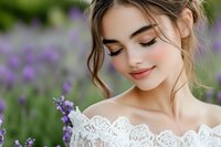 Young woman in white lace dress smiling with closed eyes among blooming lavender field, natural makeup, romantic summer portrait with soft purple bokeh background.