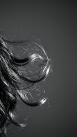Flowing wavy hair in motion captured in dramatic black and white photography with dynamic movement and texture against dark background.