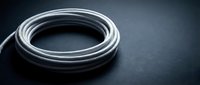 White electrical cable coiled on dark surface for industrial wiring projects and construction applications.