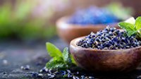 Dried black beans in wooden bowl with fresh mint leaves on rustic table. Healthy legumes protein source for vegetarian cooking and nutrition.