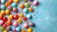 Colorful candy balls and chocolate truffles scattered with pink sugar pearls on textured turquoise background. Festive sweet flat lay composition.
