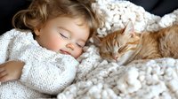 Peaceful sleeping child and ginger cat cuddling together on white cozy knitted blanket, tender moment of afternoon nap showing friendship between pets and kids.