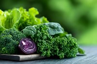 Fresh green kale leaves, broccoli florets and sliced purple cabbage arranged on dark wooden surface against blurred natural background. Healthy eating concept.