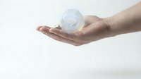 Hands holding glowing lightbulb with gear mechanism inside representing innovation and creative problem solving for business technology concepts.