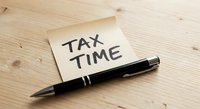 Tax time reminder note with black pen on wooden desk for accounting and financial planning preparation.