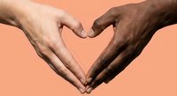 Two diverse hands forming heart shape symbol representing unity, love, friendship and racial harmony on coral background for social campaigns.