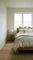 Serene bedroom interior with wooden bed, neutral linen bedding, white nightstand lamp, and large windows overlooking nature for home decor and design inspiration.