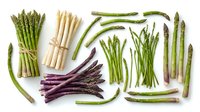 Fresh asparagus spears in green, white and purple varieties arranged on white background. Organic vegetables for healthy cooking and nutrition.