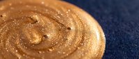 Golden glitter swirl on dark blue background, creating shimmering spiral texture. Suitable for luxury branding, cosmetics packaging, and festive design projects.