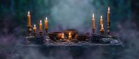 Mystical altar with burning candles, crystal ball, dried herbs and ritual items surrounded by ethereal smoke for spiritual practices and witchcraft ceremonies.