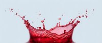 Red liquid splash with droplets frozen in motion against neutral background, suitable for beverage, cosmetics, and product marketing campaigns.