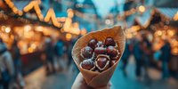 Chocolate strawberries in waffle cone against blurred Christmas market with festive bokeh lights, creating warm holiday atmosphere.