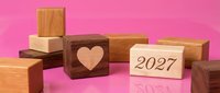 Wooden blocks with heart symbol and 2027 year number arranged on pink background, suitable for calendar designs, new year planning, love concepts, and greeting card projects.