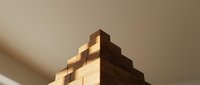 Wooden stacked blocks forming pyramid structure with warm sunlight casting shadows, suitable for business growth, education, and development concepts.