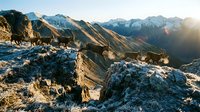 Rocky mountain landscape with dramatic peaks and golden sunrise light illuminating snow-capped summits and rugged terrain for outdoor adventure content.